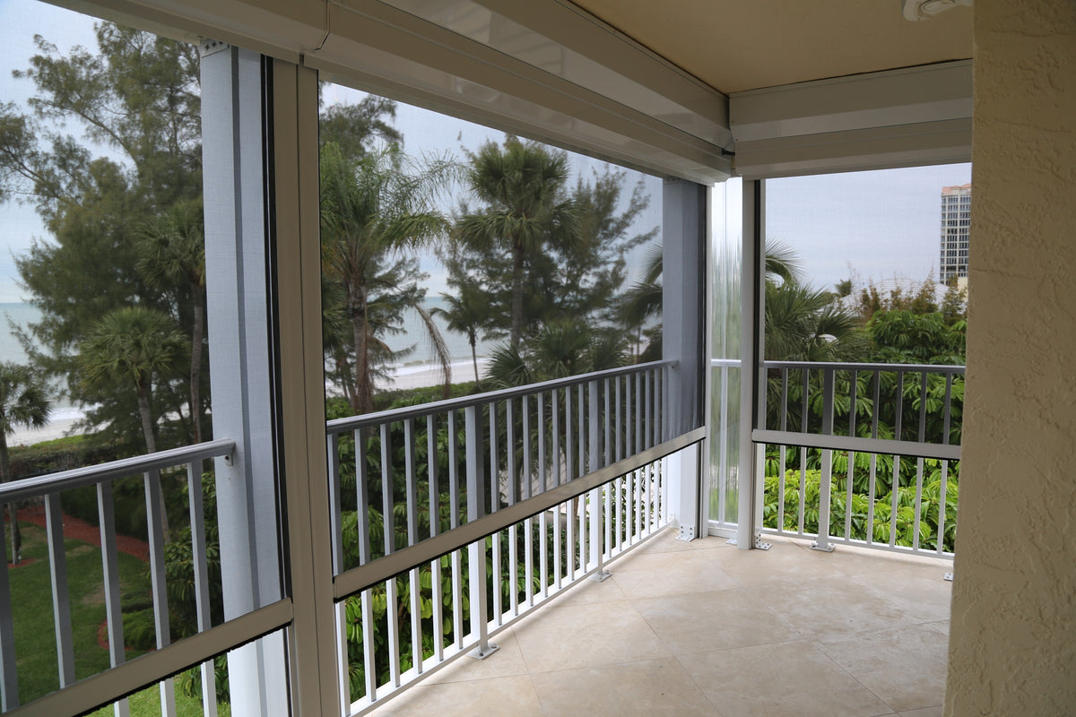 Corner condo balcony with retractable screens lowered in their side guides between the posts and railings