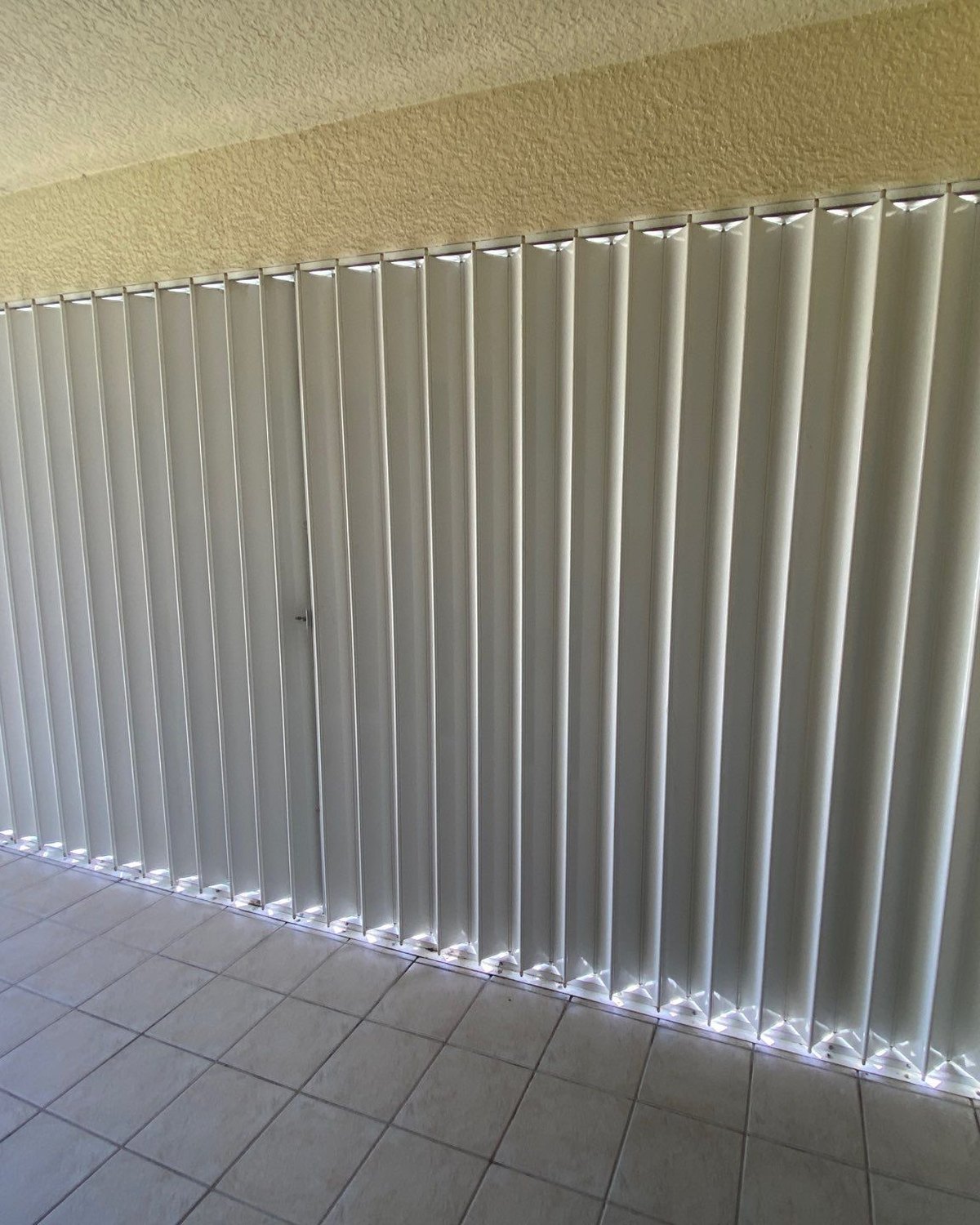 White accordion shutters closed across a wide lanai opening